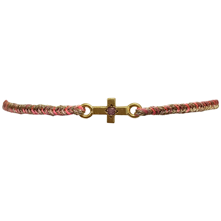 This delicate bracelet is handmade by our team of master artisans using metallic threads and a gold cross charm encrusted with a sparkling pink tourmaline stone. It&