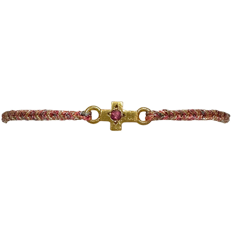This delicate bracelet is handmade by our team of master artisans using metallic threads and a gold cross charm encrusted with a beautiful pink tourmaline stone. It&