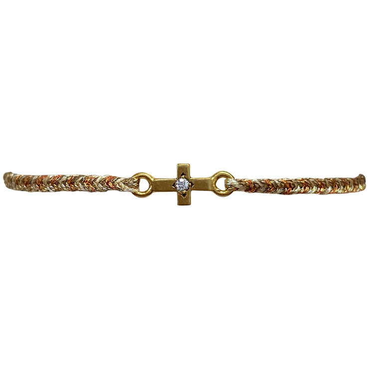 This delicate bracelet is handmade by our team of master artisans using metallic threads and a gold cross charm encrusted with a sparkling quarzt stone. It&