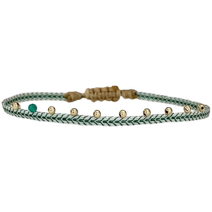 This LeJu bracelet has been handwoven in Colombia by our team of artisans using Polyester threads in green tones, 14 k gold filled beads and a green onyx stone  This can be worn solo or with your favourite pieces.  Details:      Polyester threads     Green onyx semi-precious stone     14k Gold filled details       Handwoven adjustable bracelet     Width 2mm     Can be worn in the water