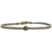 This delicate bracelet is handmade by our team of master artisans using polyester threads and a gold charm encrusted with a green kyanite stone.  Beautifully crafted and designed to make you feel beautiful and confident, this stunning piece will be sure to be your favorite wardrobe essential.  Details:      Green kyanite semi-precious stone     Gold Vermeil setting     Adjustable handwoven bracelet     Women bracelet     Width 5mm