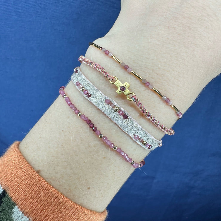 This delicate bracelet is handmade by our team of master artisans using metallic threads and a gold cross charm encrusted with a beautiful pink tourmaline stone. It&