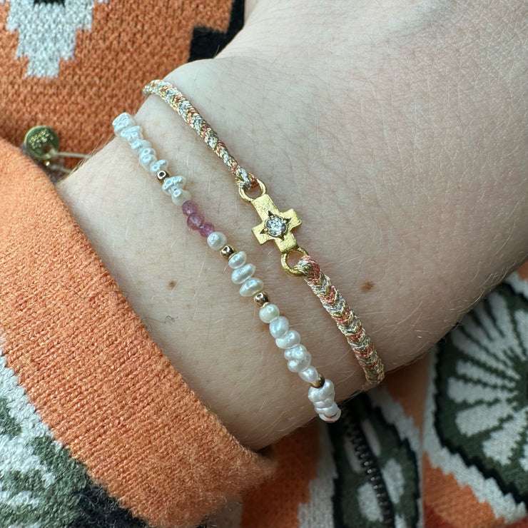 This delicate bracelet is handmade by our team of master artisans using metallic threads and a gold cross charm encrusted with a beautiful zircon stone. It&