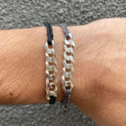   This bracelet has been handwoven in Colombia by our tema of master artisans. It features a strap in black tones with a central chain in 925 sterling silver. This masculine design looks great worn solo or stacked with other pieces.  Details:      925 sterling silver centrpiece     Italian wax threads     Adjustable handwoven bracelet     Width 7mm      Can be worn in the water