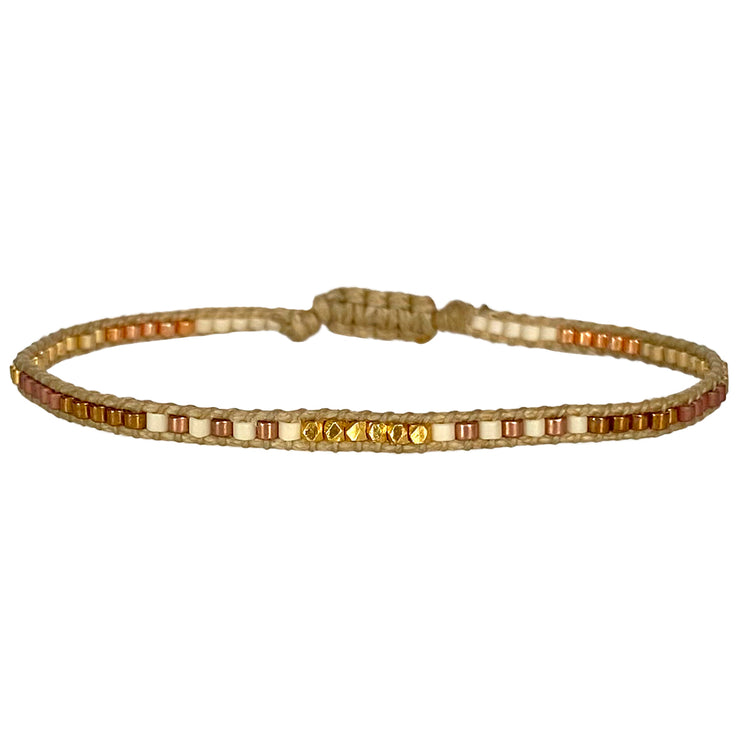 Handwoven in Colombia, this feminine bracelet features a single row of Japanese glass beads in gold and brown tones and gold faceted beads  Wear this stylish bracelet alone or as a part of a bracelet layering combination, with your favourite jeans & t-shirt!  Details:  -Gold faceted beads  - Japanese glass beads  - Width: 2mm  - Adjustable bracelet 