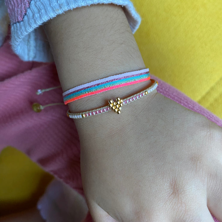 Handwoven with single row of Japanese glass beads, in pastel colours. Featuring a fun central heart detail perfect for everyday wear.  Details  - Japanese glass beads  - Adjustable pull cord  - Kids bracelet  - Width 2mm   